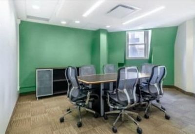 Modern conference room with green accent walls and ergonomic mesh chairs.