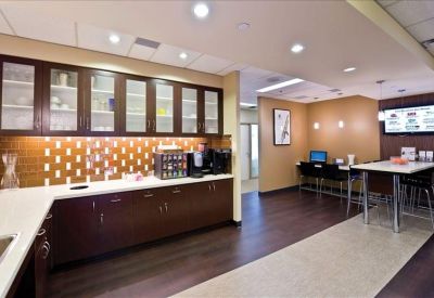 Modern office kitchen and breakroom with dark cabinetry and tile backsplash.