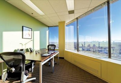 Bright corner office with floor-to-ceiling windows and green accent wall.