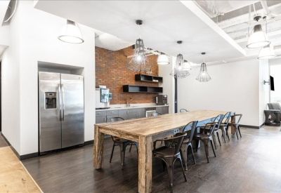 Communal kitchen and dining area featuring a brick accent wall and stainless steel fridge.