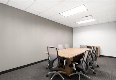 Bright conference room with a large wooden table and grey ergonomic chairs.