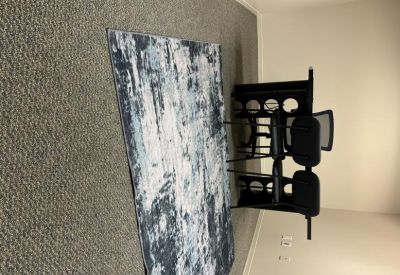 Office suite featuring a blue and white abstract rug and a black desk.