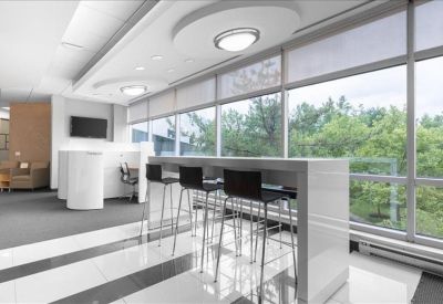 Bright breakroom area with high-top seating and a view of lush green trees.