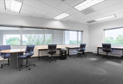 Spacious open-plan office with multiple desks and large windows.