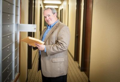 A hallway lined with mailboxes and a professional staff member holding an envelope.