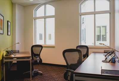 Private office featuring two desks, mesh chairs, and large arched windows.