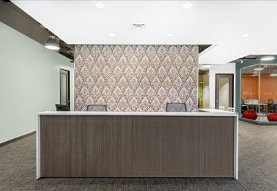 Professional reception desk with a wood-panel facade and a decorative patterned wallpaper backdrop.