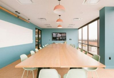 Spacious boardroom with a long wooden table, teal walls, and large windows.