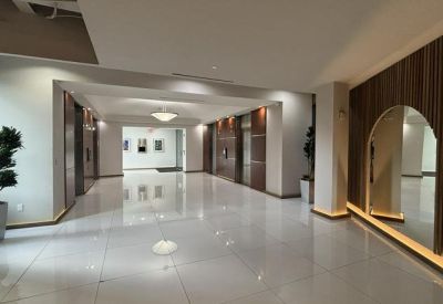 Sleek elevator lobby with polished white floors, wood accents, and warm integrated lighting.