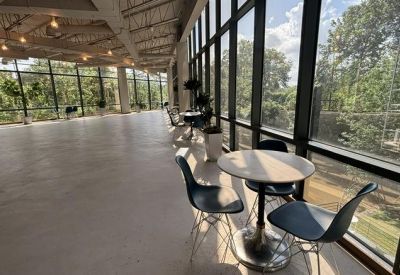 Bright breakout space featuring floor-to-ceiling windows and cafe tables overlooking lush greenery.