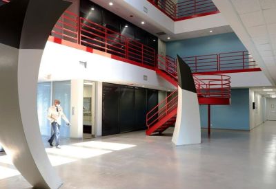 Modern multi-level atrium featuring a bright red staircase and large curved sculptures.