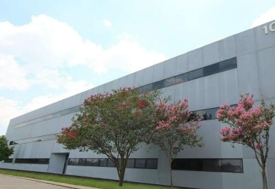 Long building facade with horizontal window bands and flowering pink crape myrtle trees.