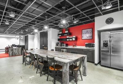 Industrial-style kitchen area with a long communal table and red feature wall.