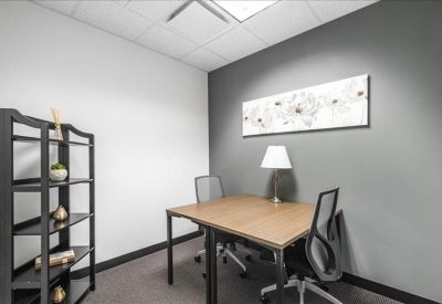 Minimalist two-person private office with a grey feature wall and floral artwork.