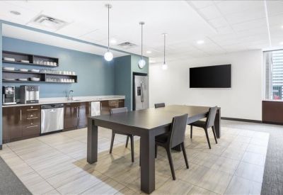 Modern communal kitchen and break area with a large dining table and blue walls.