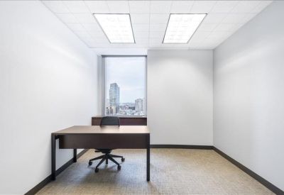Bright private office with dark wood desk and city views from a large window.
