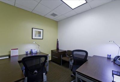 Private office suite featuring two desks, ergonomic chairs, and a pale green accent wall.