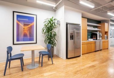 Breakout area with a kitchen, wooden floors, and a small dining table with blue chairs.