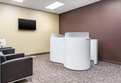 Bright breakout area with modern white privacy booths and comfortable armchairs.