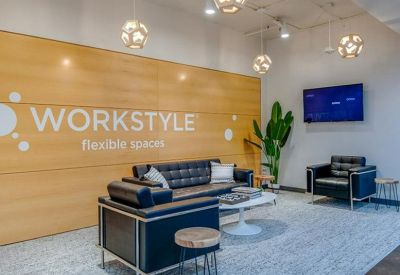 Modern communal lounge with navy sofas, wooden wall paneling, and globe pendant lights.