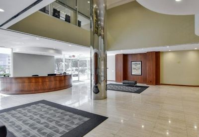 Spacious building lobby with a curved wooden reception desk and polished stone flooring.