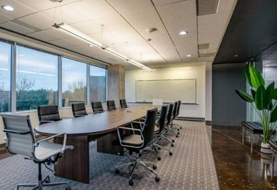 Executive boardroom featuring a large oval table, mesh chairs, and a wall-mounted whiteboard.