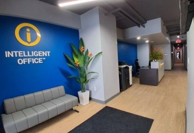 Entryway lounge area with blue branded wall and grey cushioned bench.