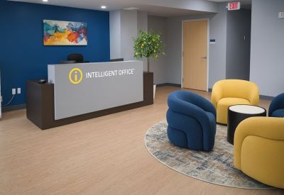 Modern reception desk with blue accent wall and colorful lounge chairs.