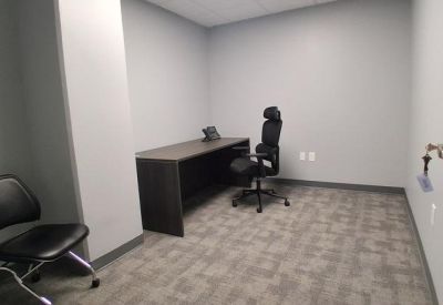 Private windowless office with dark wood desk and ergonomic chair.
