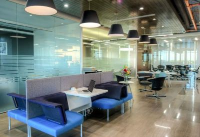 Communal lounge area with blue seating pods, a laptop workspace, and modern pendant lighting.