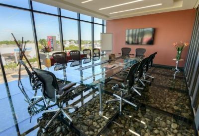 Spacious boardroom with a glass table, ergonomic chairs, and expansive city views.