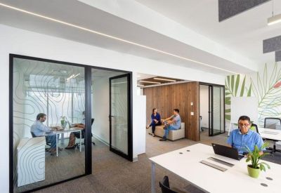 Casual lounge area and private glass office pods with warm wood paneling.