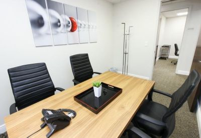 Private office with a light wood desk and black leather chairs.