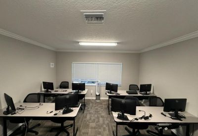 Shared workspace with several desks, computer monitors, and a central window with blinds.