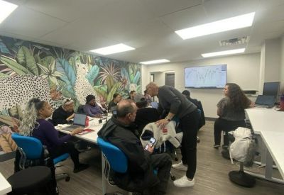 Collaborative workspace with a jungle-themed mural and people working at a central table.