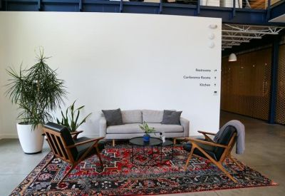 Minimalist reception area with a grey sofa and a vibrant oriental rug.