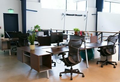 Modern open-plan workspace with ergonomic chairs and wooden desks.