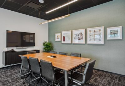 Professional conference room with a large wood table, black leather chairs, and framed wall art.