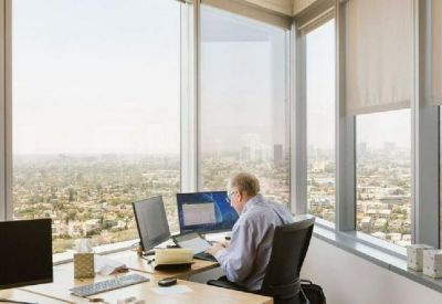 Corner office workstation with dual monitors and panoramic views of Los Angeles.