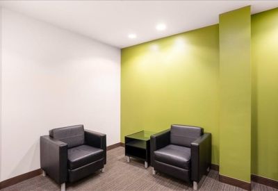 Cozy breakout area with two black leather armchairs and a green wall.