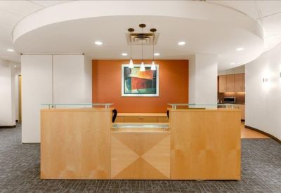 Sleek wooden reception desk backed by a feature wall and artwork.