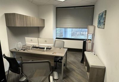 Private office with wooden desk and dual monitors.