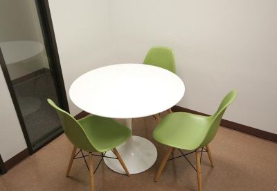Small meeting area featuring a white round pedestal table and three lime green chairs.