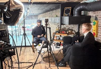 Two people recording a podcast in a studio setting with professional lighting and microphones.