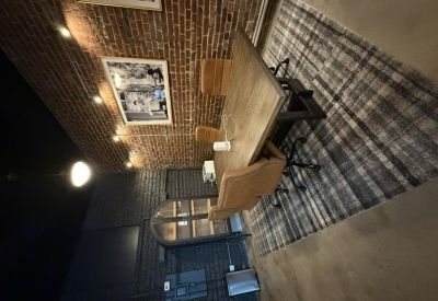 Professional meeting room featuring a wooden table and leather chairs against an exposed brick wall.