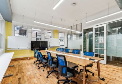 Large conference room with blue chairs, a light wood table, and multiple whiteboards.
