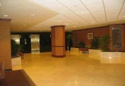 Spacious building lobby featuring polished floors, indoor plants, and a central wooden pillar.