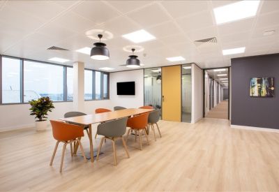 Vibrant breakout area featuring a long wooden table with orange and grey chairs.