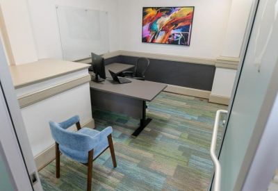 Private office suite with a desk, blue armchair, and colorful abstract wall art.
