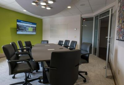 Professional conference room with black leather chairs, a long table, and a wall-mounted TV.